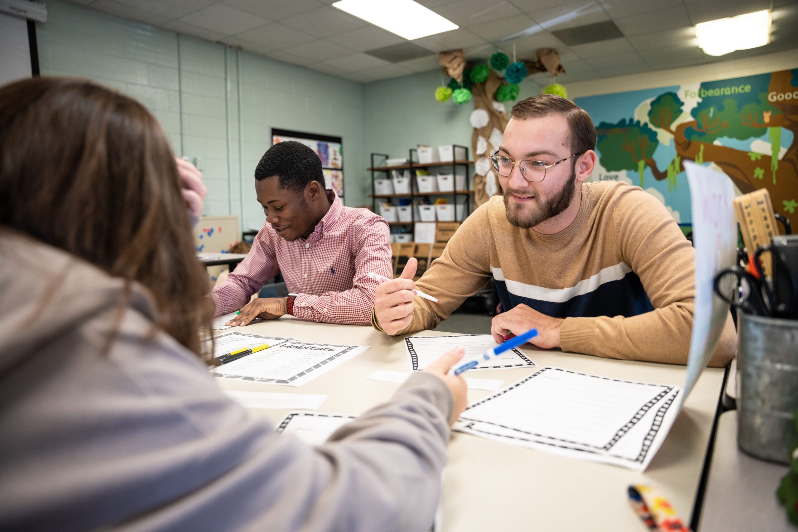 A few students around a table with a pen and a paper and talking to each other