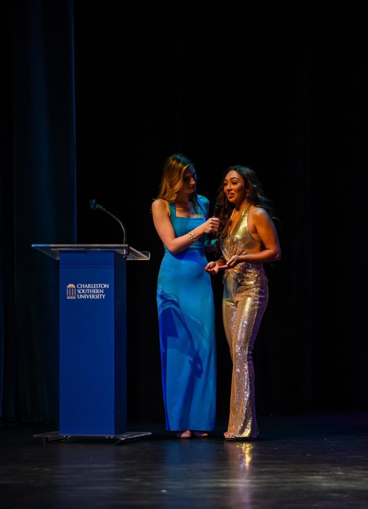 Two contestants stand on stage in pageant gowns during the Miss CSU event