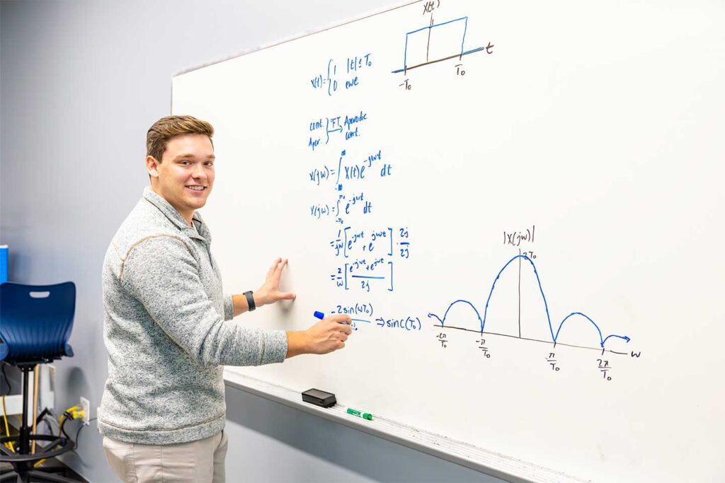 CSU Engineering student working a problem on a dry erase board.