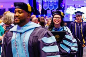 Charleston Southern University graduate student graduation. Female student smiling as she walks in the processional.